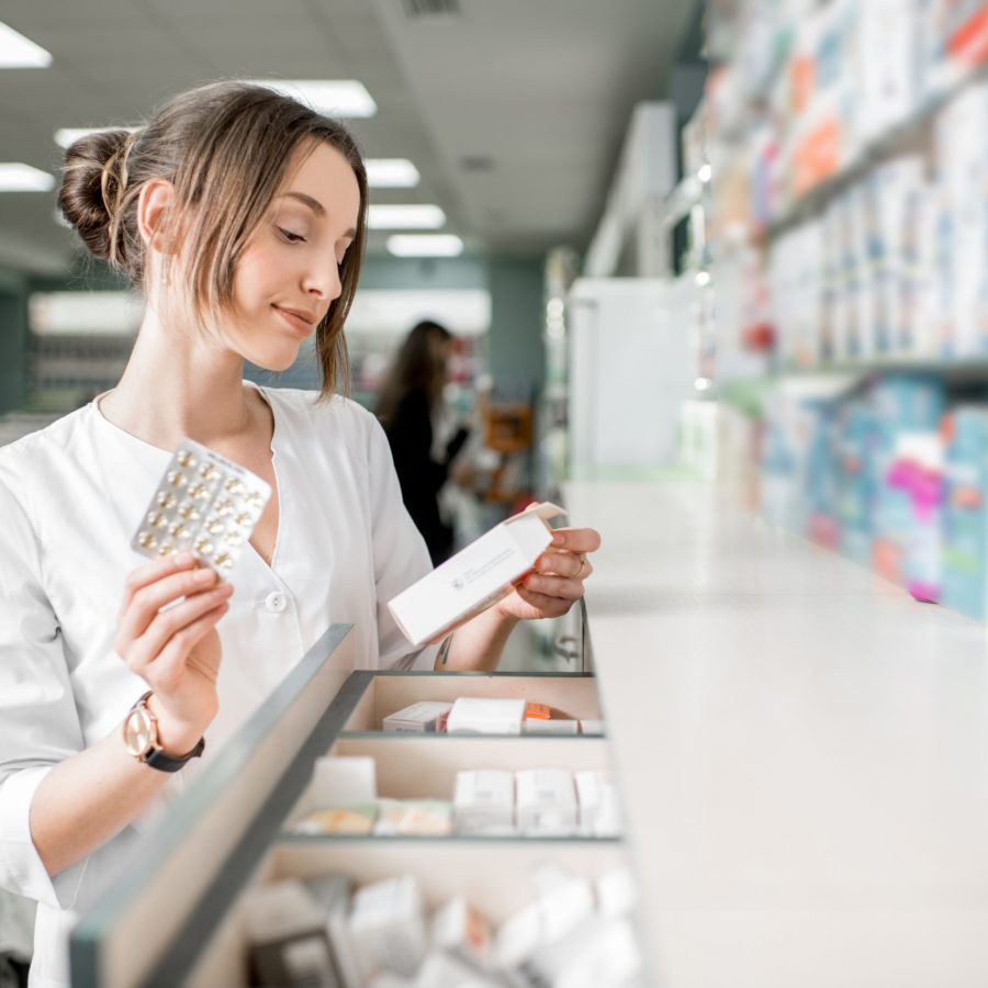 Young woman pharmacist searching for a medication in the storage of the pharmacy store