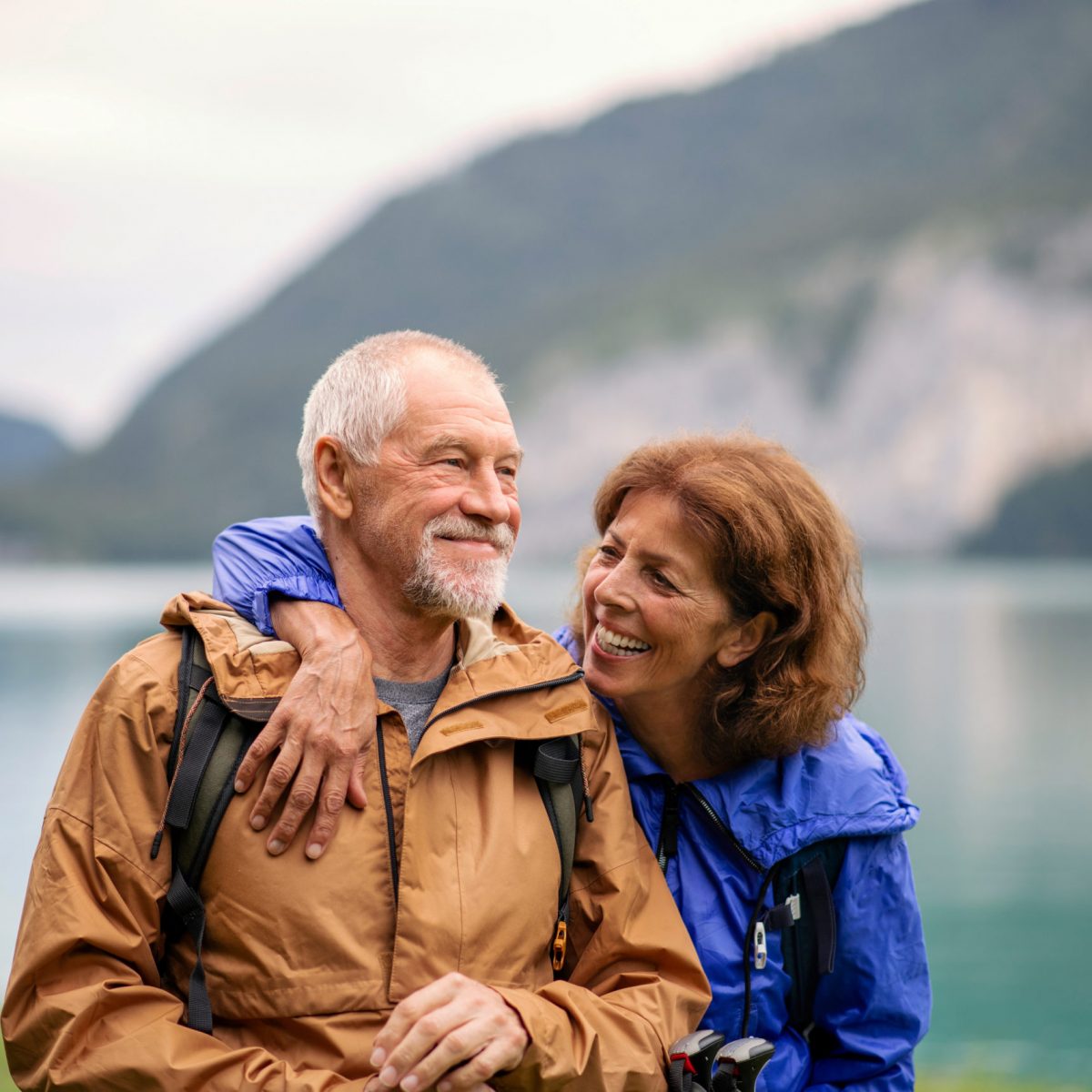A senior pensioner couple hiking by lake in nature, resting.